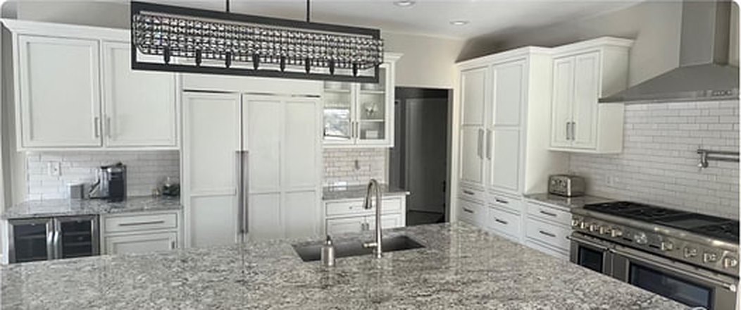 Remodeled kitchen with white shaker cabinets, granite island and pendant lighting
