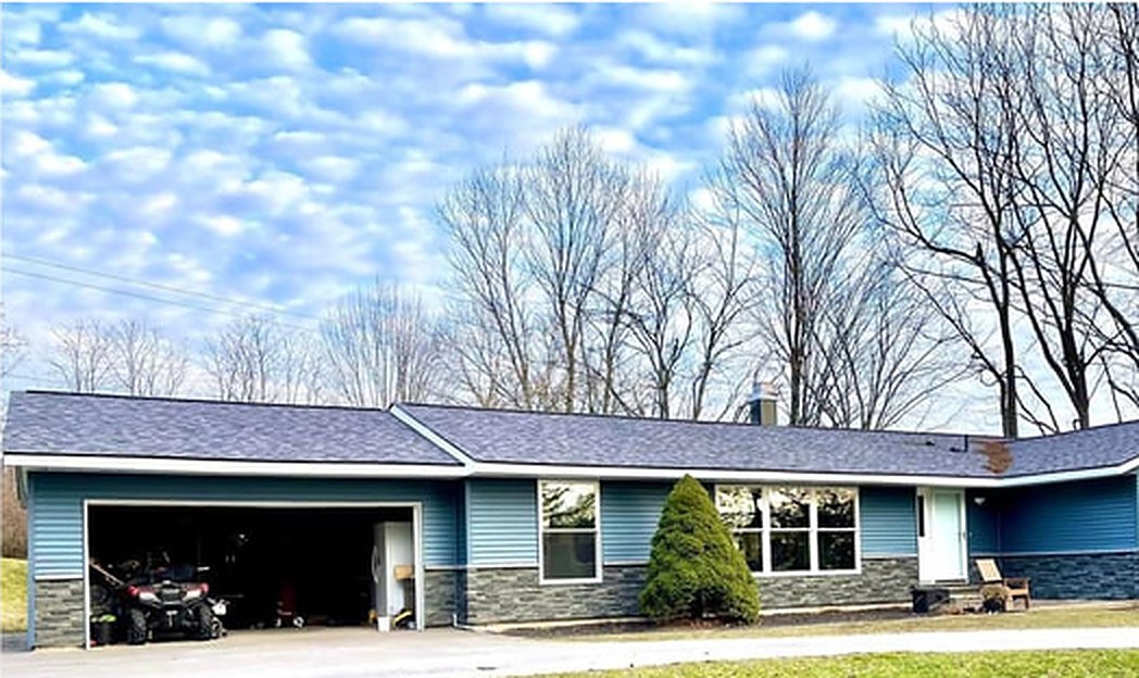 Ranch home after new blue siding and stone veneer by HomePro Services