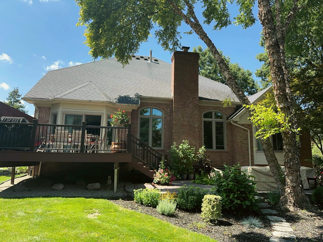 The back of a brick home with a new elevated deck and fresh plantings, a HomePro job