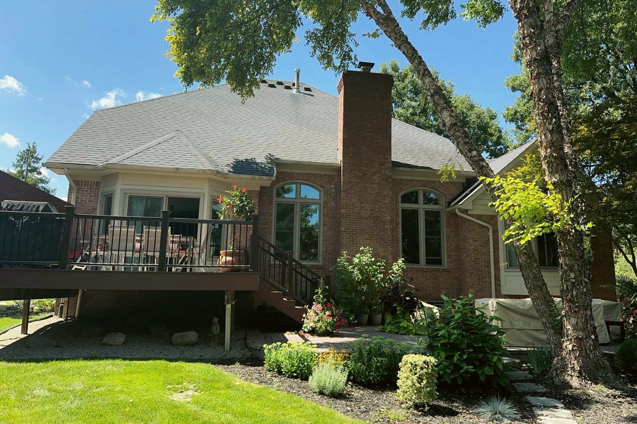 A new elevated deck on the back of a brick home with a stone chimney, a HomePro job