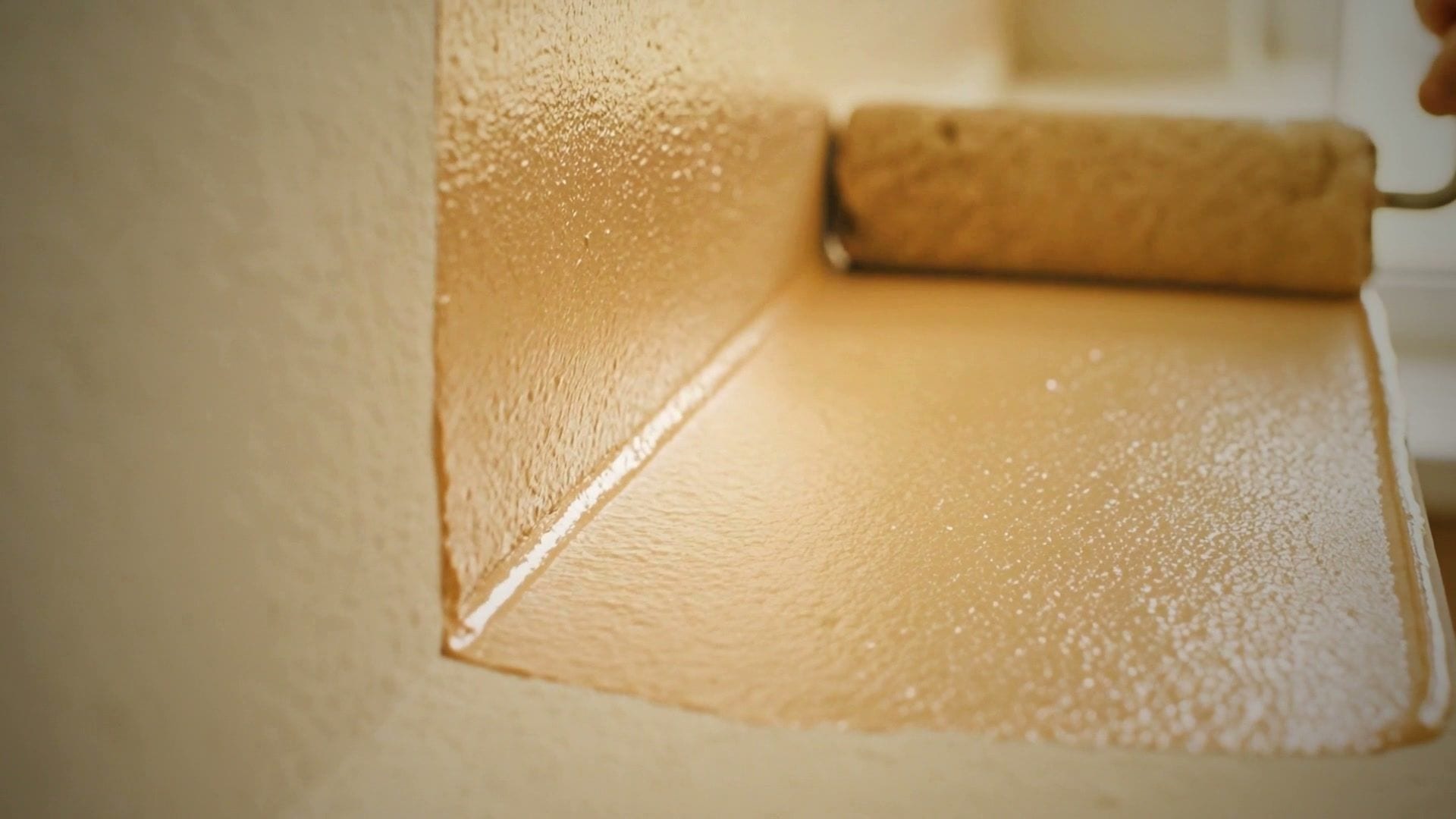 A roller laying a fresh coat of warm white paint on a wall