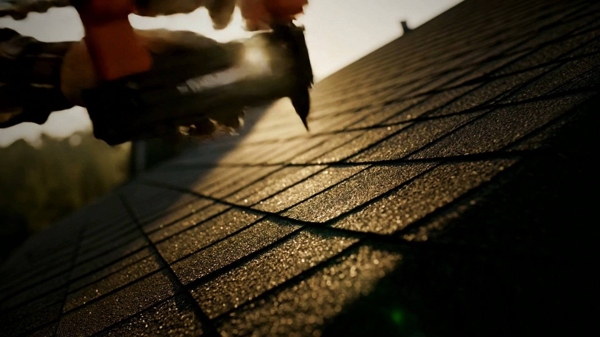 Architectural shingles being nailed down at golden hour