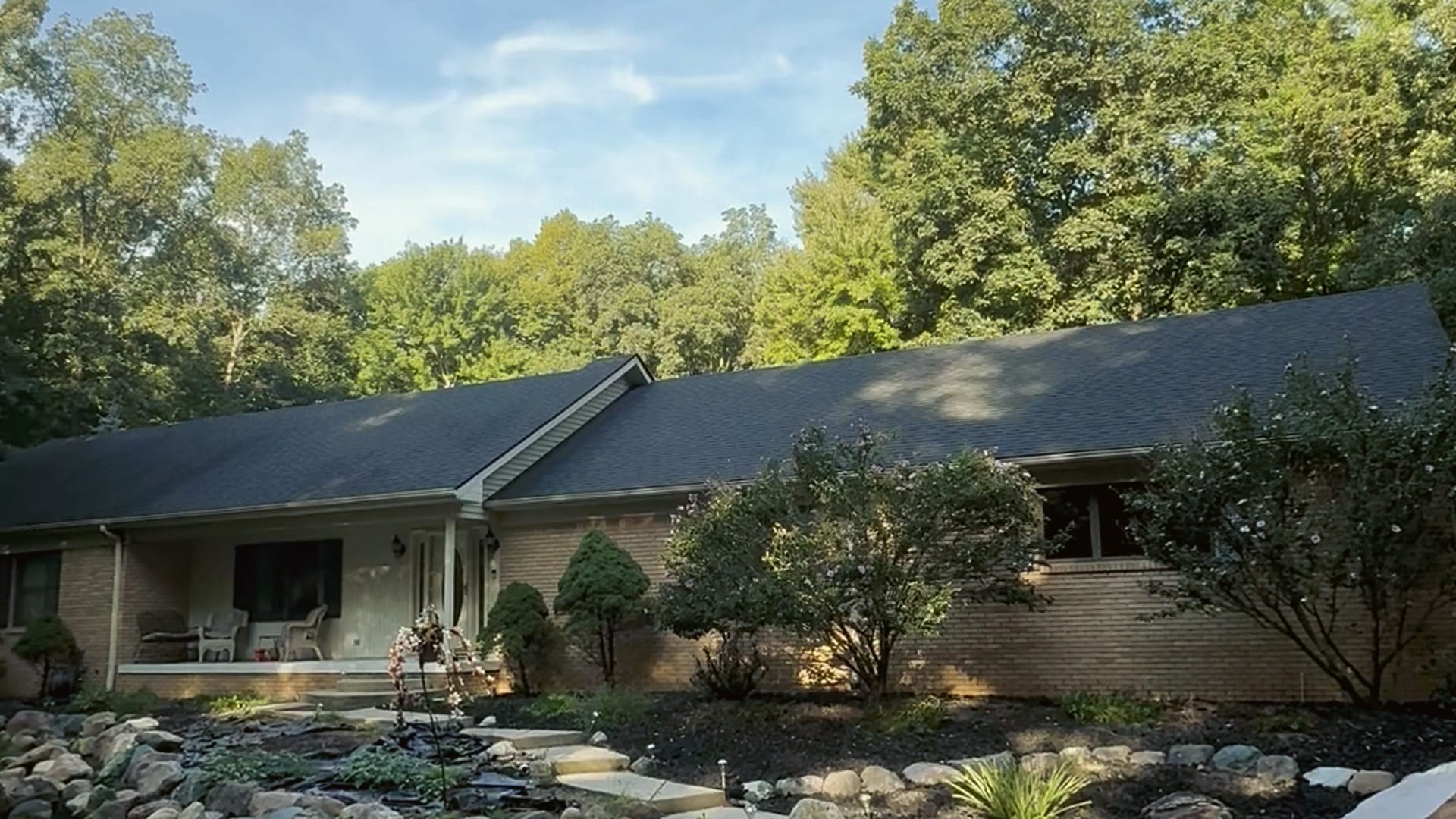 A finished brick ranch from the street, the porch lit, a HomePro job