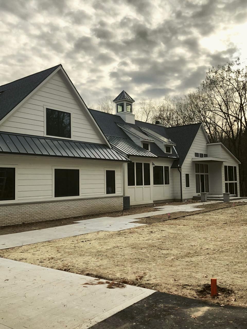 A finished modern farmhouse with a standing-seam metal roof, shingle roof and cupola, a HomePro job